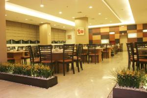 un restaurante con mesas de madera, sillas y plantas en Grand Asia Hotel Jakarta, en Yakarta