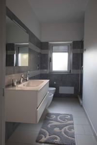 a bathroom with a sink and a toilet and a window at Cala Del Faro Beach Villas in Cittadella del Capo