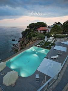 an overhead view of a swimming pool with umbrellas and the ocean at Cala Del Faro Beach Villas in Cittadella del Capo