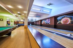 een bowlingbaan met pinnen en een pooltafel bij Hotel Clermont in Covasna