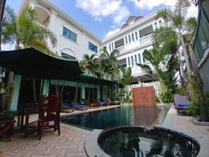 una piscina en un hotel con sillas y sombrilla en Central Night Hotel, en Siem Reap