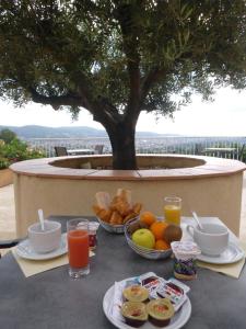 a table with plates of food on a table with a tree at Logis Hotel Le Col De L'ange in Draguignan