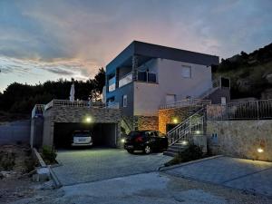 ein Haus mit einem Auto auf einem Parkplatz in der Unterkunft Villa Sara with Sea View and Private Heated Pool in Omiš