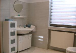 een witte badkamer met een wastafel en een spiegel bij Apartment Heilbrünnchen in Emmelshausen