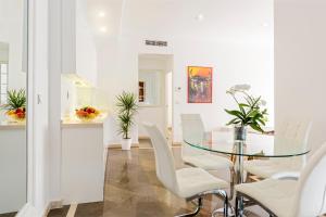 comedor con mesa de cristal y sillas blancas en Genteel Home Sagrado Corazón, en Granada