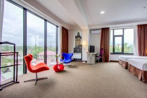 a hotel room with a bed and chairs and windows at Hotel Bridges Bishkek in Bishkek