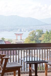 una mesa y bancos en un balcón con vistas en Kikunoya en Miyajima