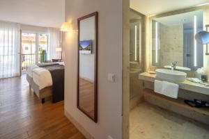 un bagno con un lavandino, un letto e uno specchio di Waldhotel Stuttgart a Stoccarda
