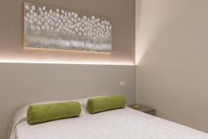 Una cama blanca con almohadas verdes encima. en Casa Colibrì nel cuore della città antica, en Verona