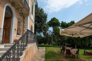 a patio with tables and an umbrella next to a building at Tenuta Villa Colle Sereno in Montemarciano