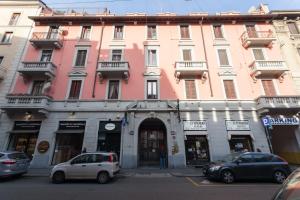 un edificio rosa con coches estacionados frente a él en New Apartment Marghera, en Milán