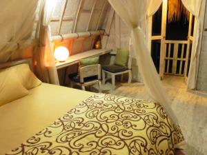 a bedroom with a bed and a desk and a window at Uma Nandhi Ubud Natural Cottage in Tegalalang