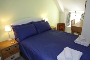 Schlafzimmer mit einem blauen Bett und einem Holztisch in der Unterkunft Saffron House in Fowey