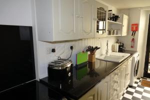 a kitchen with white cabinets and a black counter top at Saffron House in Fowey