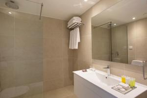 a bathroom with a shower, sink, and mirror at Venus Beach Hotel in Paphos