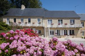 une maison avec des fleurs roses devant elle dans l'établissement Le Clos Saint Jean, à Sainte-Honorine-des-Pertes