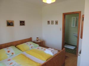 a bedroom with a bed with yellow sheets and a bathroom at Fewo Zak in Sankt Kanzian