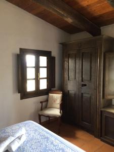 a bedroom with a bed and a chair and a window at Agriturismo Il Muto di Gallura in Aggius