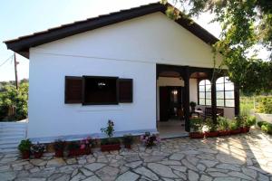 a white house with a porch and a patio at Katomeris Beach House in Roda