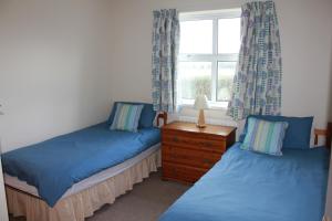 two twin beds in a room with a window at Giant's Causeway Holiday Cottages in Bushmills