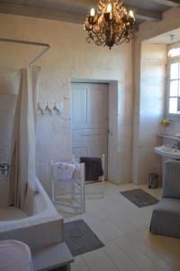 uma casa de banho com um lustre, uma banheira e uma cadeira. em Le Petit Logis em Rouillac