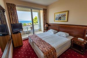 a hotel room with a bed and a large window at Dolphin Resort & Conference in Kalamos