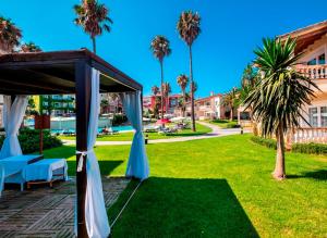 a gazebo in a park with palm trees at Aparthotel HG Jardin de Menorca in Son Bou