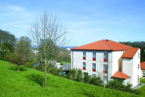 un edificio blanco con techo naranja en una colina verde en Inverness Youth Hostel en Inverness