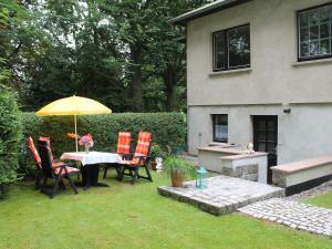 a table and chairs with an umbrella in a yard at Charming Apartment in Kr pelin with Barbecue in Kröpelin
