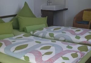 a bed with a colorful comforter and a sink at Haus Schnitzler in Wasserburg am Bodensee