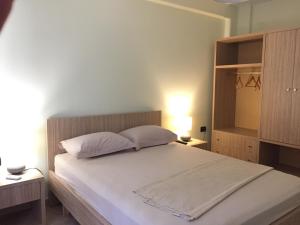sypialnia z dużym białym łóżkiem z 2 poduszkami w obiekcie Andi Apartments w Tiranie