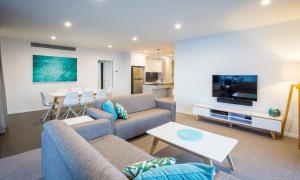 a living room with a couch and a tv at Boardwalk Burleigh Beach - Official in Gold Coast