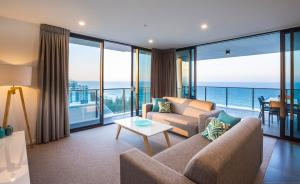 a living room filled with furniture and a large window at Boardwalk Burleigh Beach - Official in Gold Coast