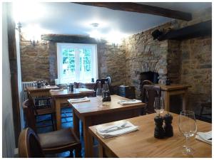 a restaurant with wooden tables and chairs and a fireplace at Bridge House in Bampton