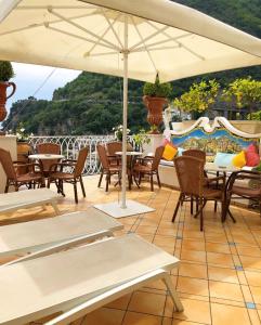 a patio with tables and chairs and an umbrella at Palazzo Marzoli charme Resort - Small Luxury Hotel in Positano