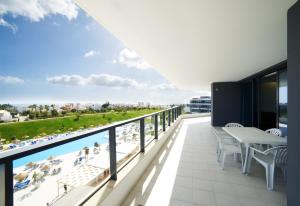a balcony with a view of the pool and beach at RR Alvor Baía Resort in Alvor