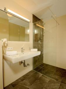 W łazience znajduje się umywalka i przeszklony prysznic. w obiekcie Hotel Burgschrofn w mieście Tux