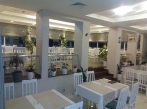 a restaurant with white tables and white chairs and potted plants at Karavan 123 in Raška