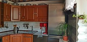 a kitchen with wooden cabinets and a stainless steel refrigerator at Pensjonat Nostalgia - w cenie rowery, parking, sauna in Kołobrzeg