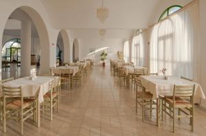 una sala da pranzo con tavoli e sedie bianchi di Alexandra Beach a Città di Kos