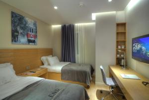 a hotel room with two beds and a desk and a tv at Endless Suites Taksim in Istanbul