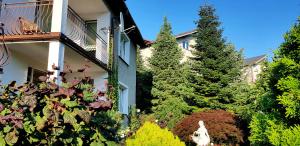 a garden in front of a house with trees at Pensjonat Nostalgia in Kołobrzeg