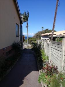 a driveway leading to a house with a fence and palm trees at A Wave from it all in Port Shepstone