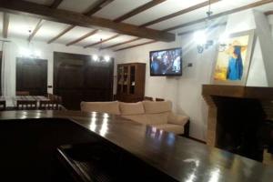 sala de estar con sofá y TV en la pared en Casa Rural Trastámara, en Montiel