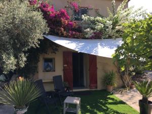 um jardim com uma casa com um guarda-chuva branco e flores em Les terrasses sur mer em Ollioules