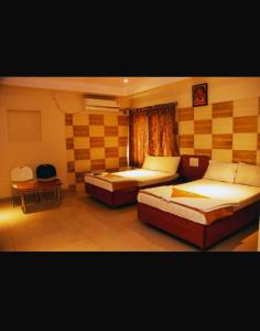 a bedroom with two beds and a table and a chair at Hotel Apple Sai Residency in Shirdi