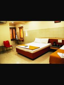 a bedroom with a large bed and a red chair at Hotel Apple Sai Residency in Shirdi