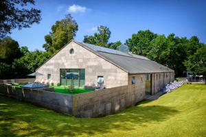 a barn conversion with a stone wall and grass at Hotel Balneario de Compostela in Brion