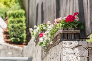 une boîte en bois remplie de fleurs sur un mur en pierre dans l'établissement Avita - suites to relax, à Ortisei