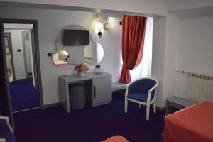 Habitación con tocador, espejo y silla. en Hotel Europolis, en Tulcea